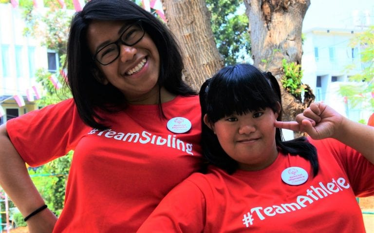 two girls wearing red shirts that say team sibling and team athlete