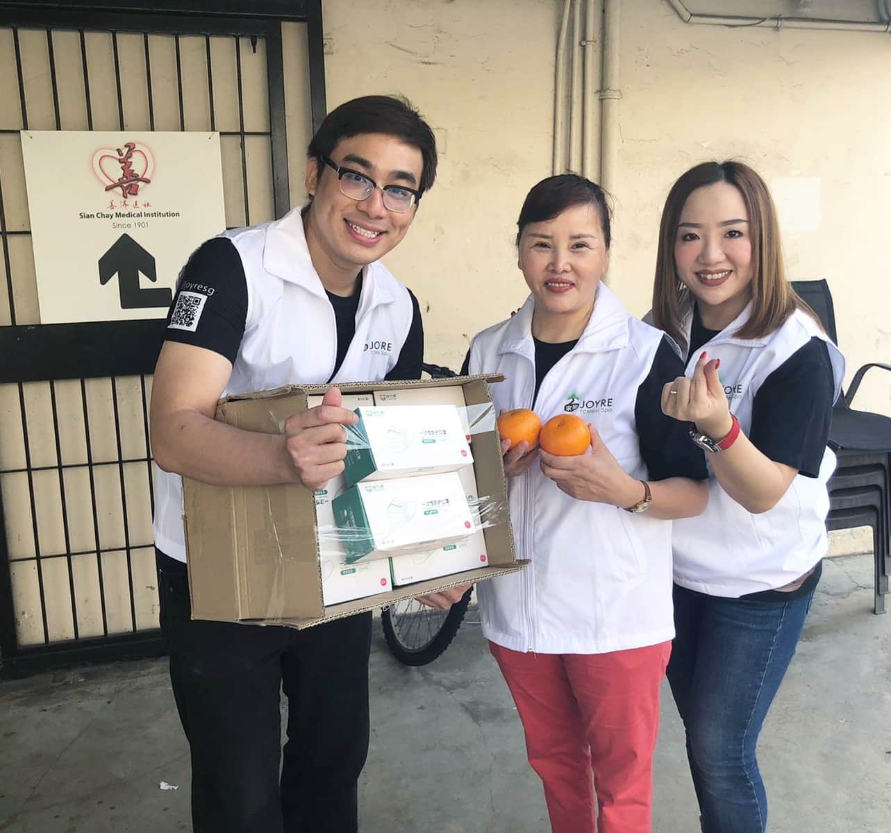 three volunteers from joyre holding oranges and a box full of masks