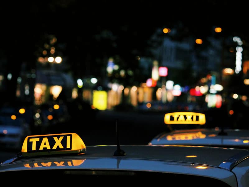 two yellow taxi signs against a dark blurry background