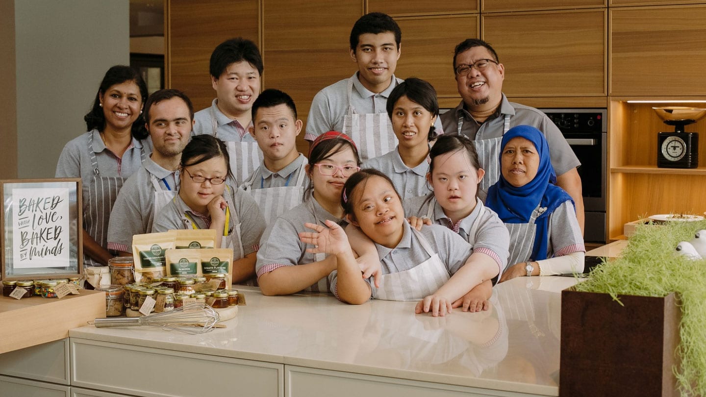 special needs bakery workers in grey uniforms posing for photo