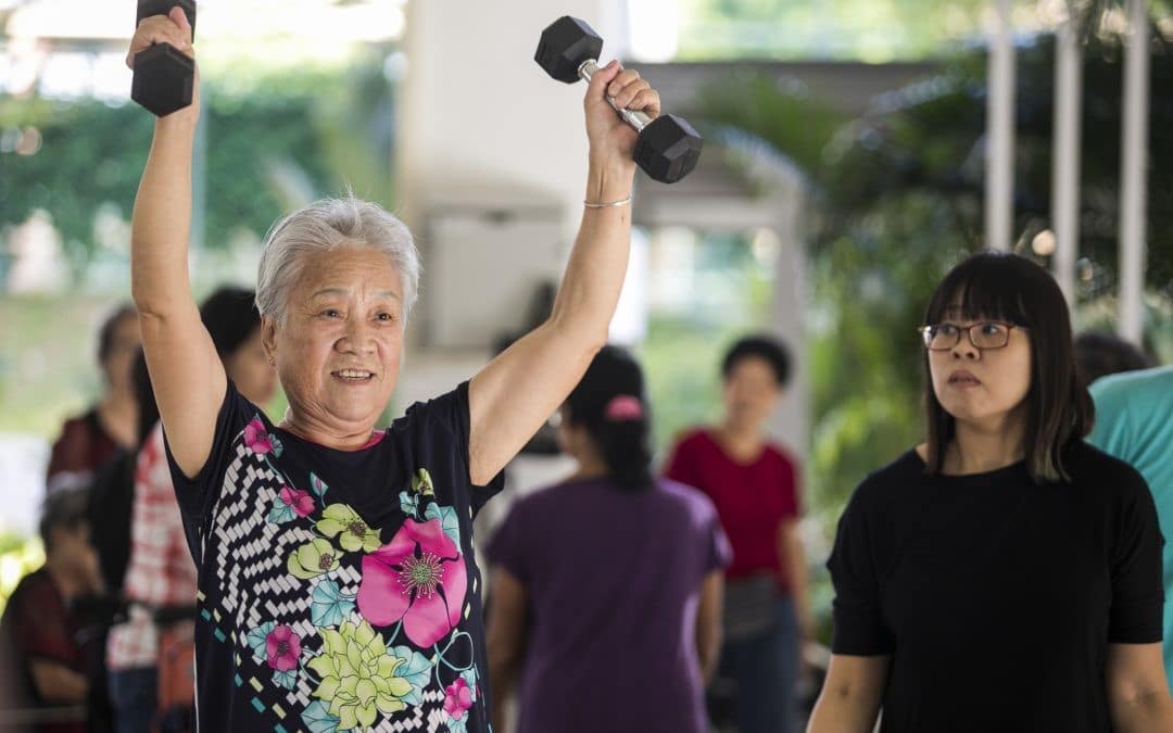 elderly woman in floral shirt raising dumbells