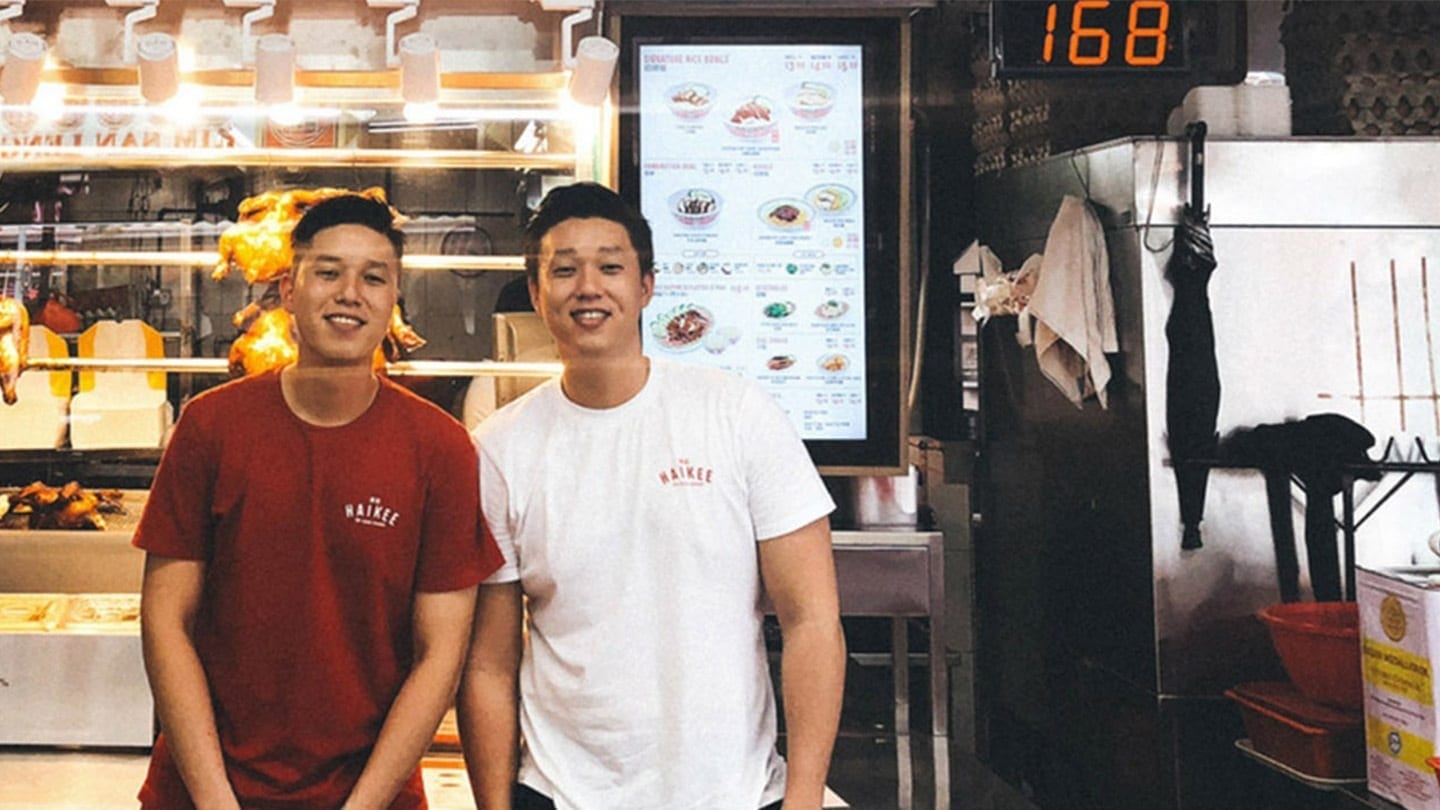 two young men standing in front of a hawker stall with a sign that says 168