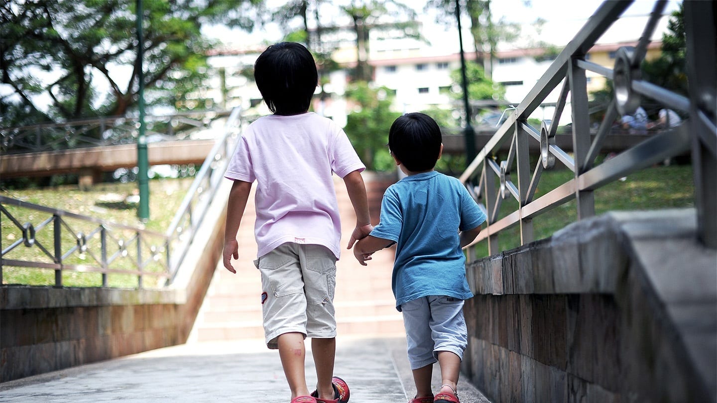 two boys walking across a bridge