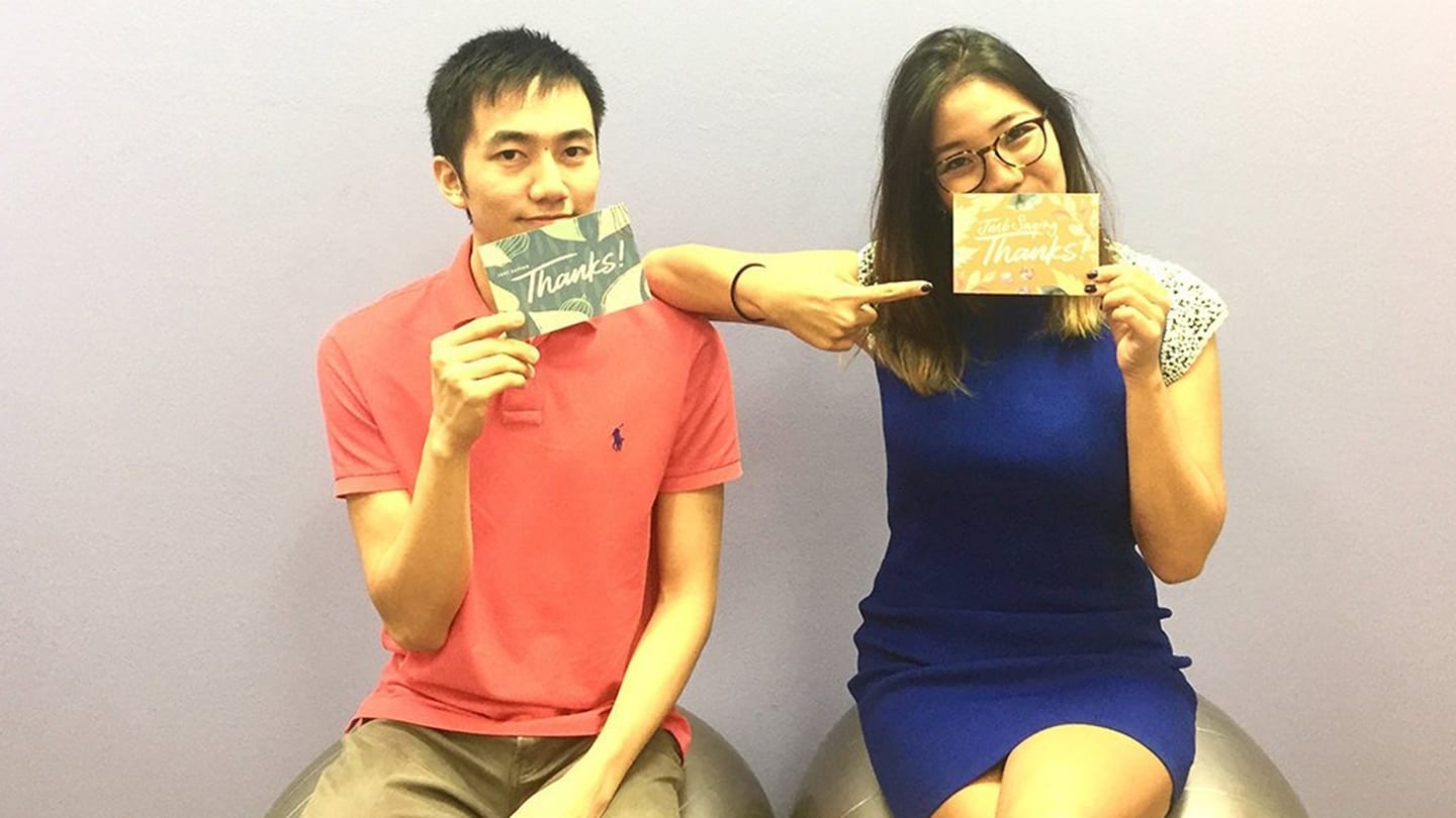 man in red shirt and woman in blue dress holding up cards that say thanks
