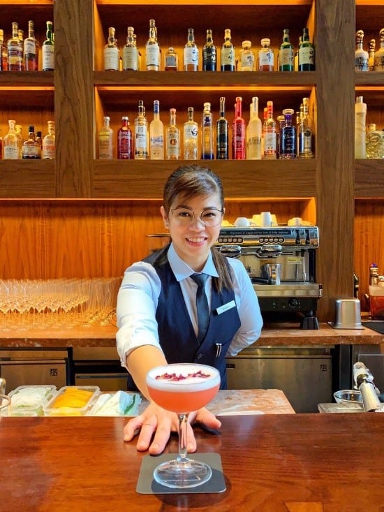 bartender serving you an orange-coloured cocktail