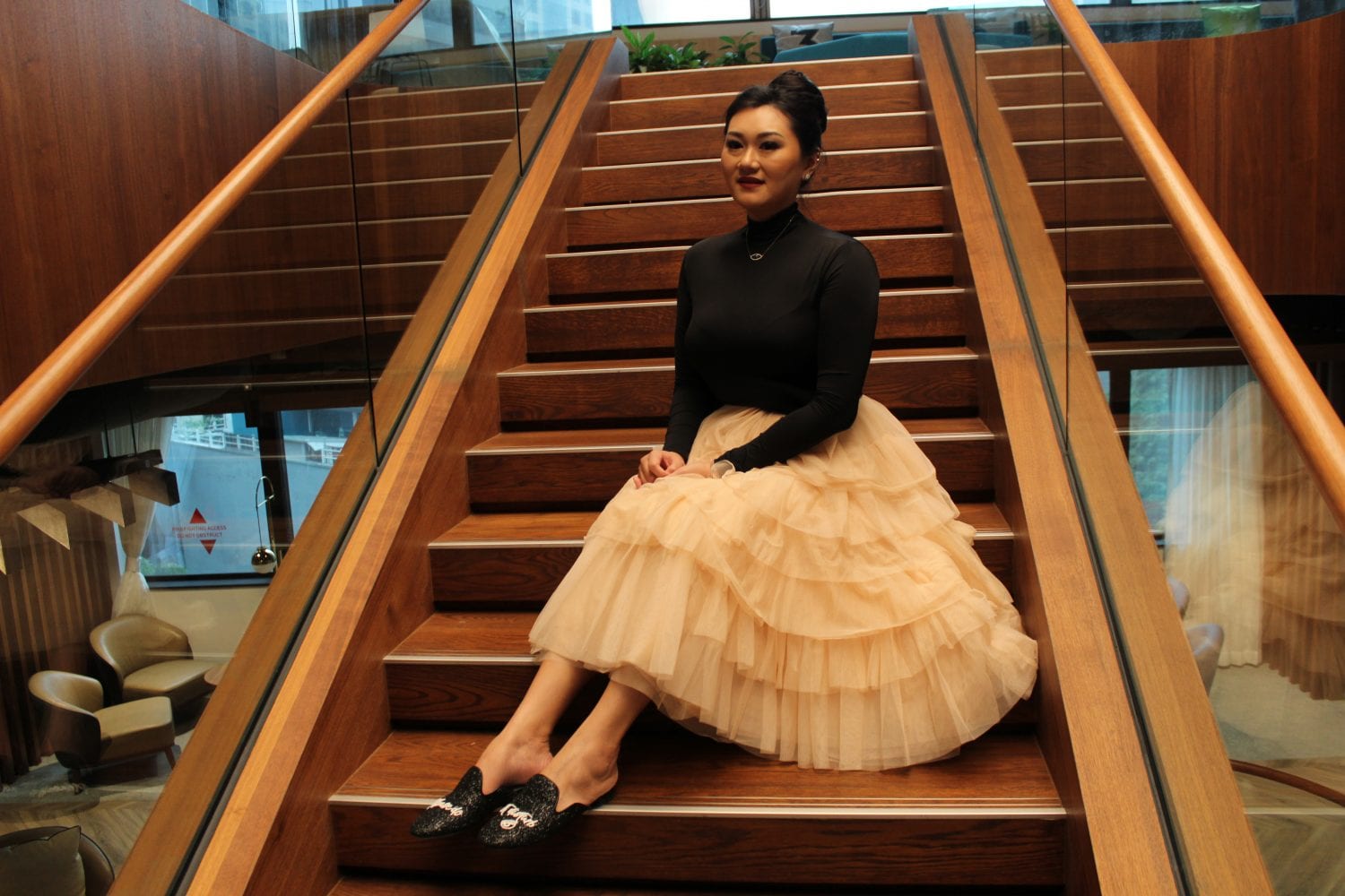 woman in black long-sleeved blouse and tiered skirt posing on the stairs